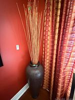Full view of vase with reeds against red wall