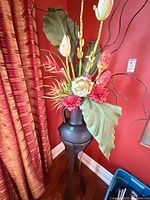 Full view of vase on stand with faux flowers