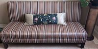 Front view of striped fabric sofa with pillow