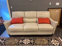 Front view of La-Z-Boy cream leather sofa with two red pillows