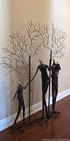 Full view of welded metal floor sculpture with three figures and tree branches
