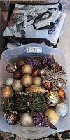 Top view of plastic bin filled with assorted ornaments and folded tote on top