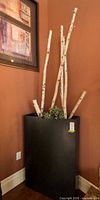 Full view of black floor planter with birch branches and faux ivy