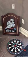 Closed cabinet showing The Ships Inn artwork next to removed dartboard