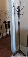 Full view of wooden coat rack showing post, hooks and base