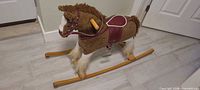 Side view of brown/white faux-fur rocking horse on wooden runners