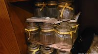 Stacked clear ribbed glass jars with lids and yellow ribbons
