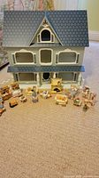 Front view of wooden dollhouse and all miniature furniture laid out