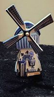Front view showing blue-and-white windmill, blades, floral motif, WITH MUSIC tag