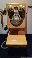 Front view showing wood case, rotary dial, brass bells, handset