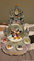 Front view showing castle, central Mickey & Minnie globe, four mini globes, and front text