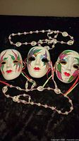 All three ceramic masks and two beaded necklaces displayed