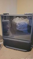 Front view of Sony rear-projection CRT TV showing screen, cabinet, speaker base