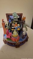 Front view showing main globe with Mickey Mouse and Goofy, smaller globe with Madame Leota, surrounding ghost figures and base details