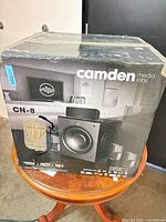 Front of boxed Camden CN-8 system with shrink wrap and wear visible