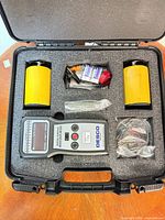 Open case showing full kit: meter, two electrodes, cables, batteries