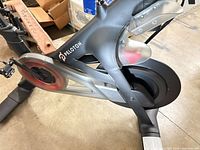 Drive side of Peloton bike showing branding, flywheel and frame