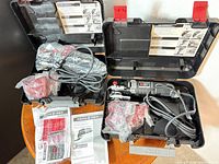 Open carrying cases showing multi-tool, accessories in bags, power cord, manuals