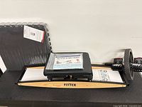 Overall view of Pro Fitter trainer on table with packaged foam mat and ab wheel