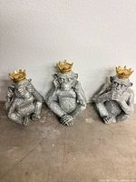 Front view of three silver resin monkey figurines with gold crowns