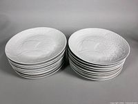 Stacked view of two stacks totaling 18 white embossed fish plates