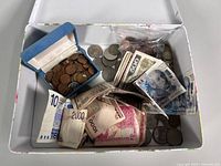 Overview of tin box with mixed coins and banknotes