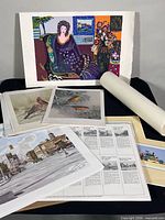 Group of assorted unframed prints and rolled artwork displayed