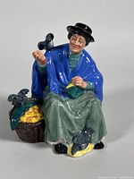 Front view of porcelain figurine showing woman feeding pigeons, basket visible