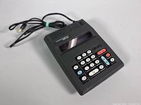 Oblique top view showing full calculator, keypad, display, attached power cord