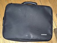 Front of closed black JUNDUN fireproof document bag showing logo and handle