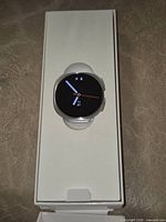 Watch seated in inner tray showing round face and strap