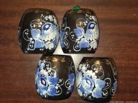 Top view of four black wooden candle holders with blue and white floral painting