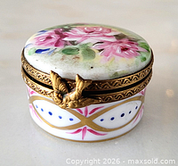 Full view of trinket box showing floral lid, metal rim, clasp