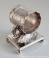 Front angled view showing floral engraving, shell support, square base, ball feet