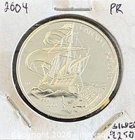 Reverse of sterling silver proof coin with ship design and anniversary dates