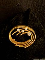 Front view of 10k gold swirl brooch with four cultured pearls
