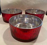 Three red textured glass bowls with metallic inner reflections