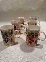 Six mugs standing, showing front botanical designs
