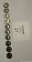Ten coins aligned obverse upward beside lot card