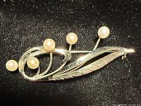 Sterling silver brooch with five pearls on black fabric