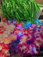 LED and non-LED flower leis illuminated, grass skirt fringe backdrop