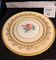 Angled view showing plate design, ruler indicating 10.5" diameter, gold rope edge and filigree detail