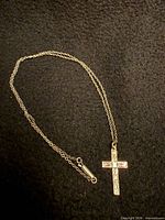 Full view of sterling silver cross pendant attached to fine chain showing clasp