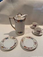 Full set showing cocoa pot, two matching saucers, two cup and saucer sets