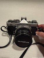 Front view of Olympus OM-1 camera with lens cap and strap