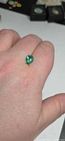 Emerald shown on fingertip for scale