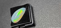 Oval crystal opal on black gem box displaying play of color