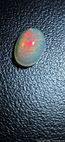 Oval fire opal showing red flash on black background