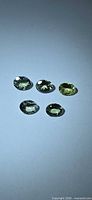 Five oval cut lemon-lime Tanzanite gemstones laid out on flat surface