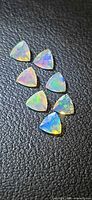Seven triangular opal gemstones on black background